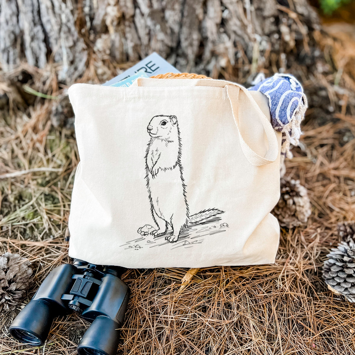 Canvas tote bag printed with a detailed black ink illustration of a Belding's ground squirrel standing upright, resting on dry grass beside a pair of binoculars.