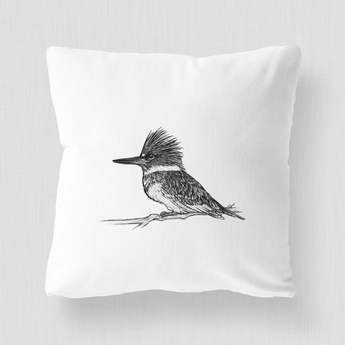 White pillow cover printed with a detailed black ink sketch of a belted kingfisher perched on a branch.
