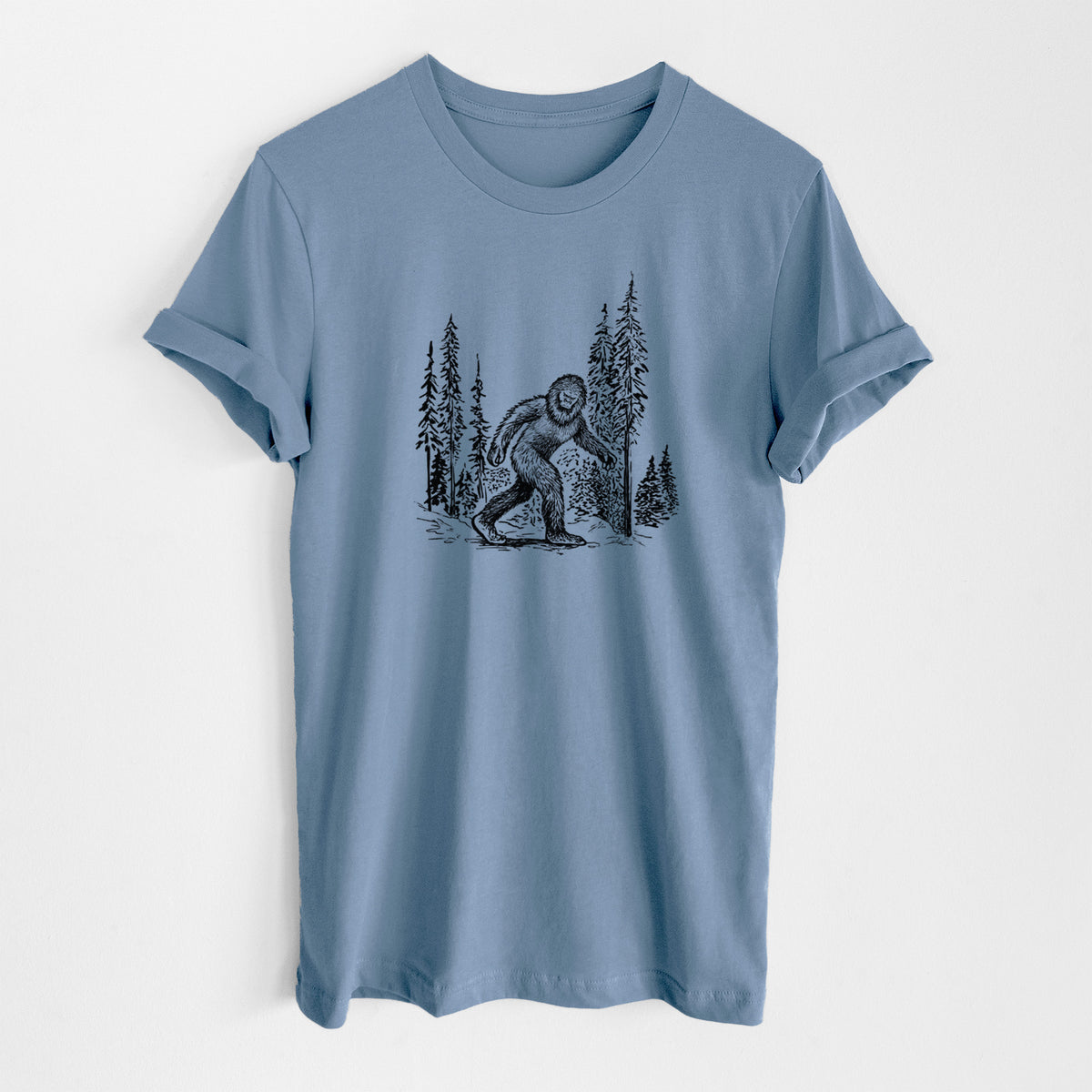 Steel blue lightweight cotton t-shirt laid flat, printed with a black ink illustration of Bigfoot walking through a pine forest.