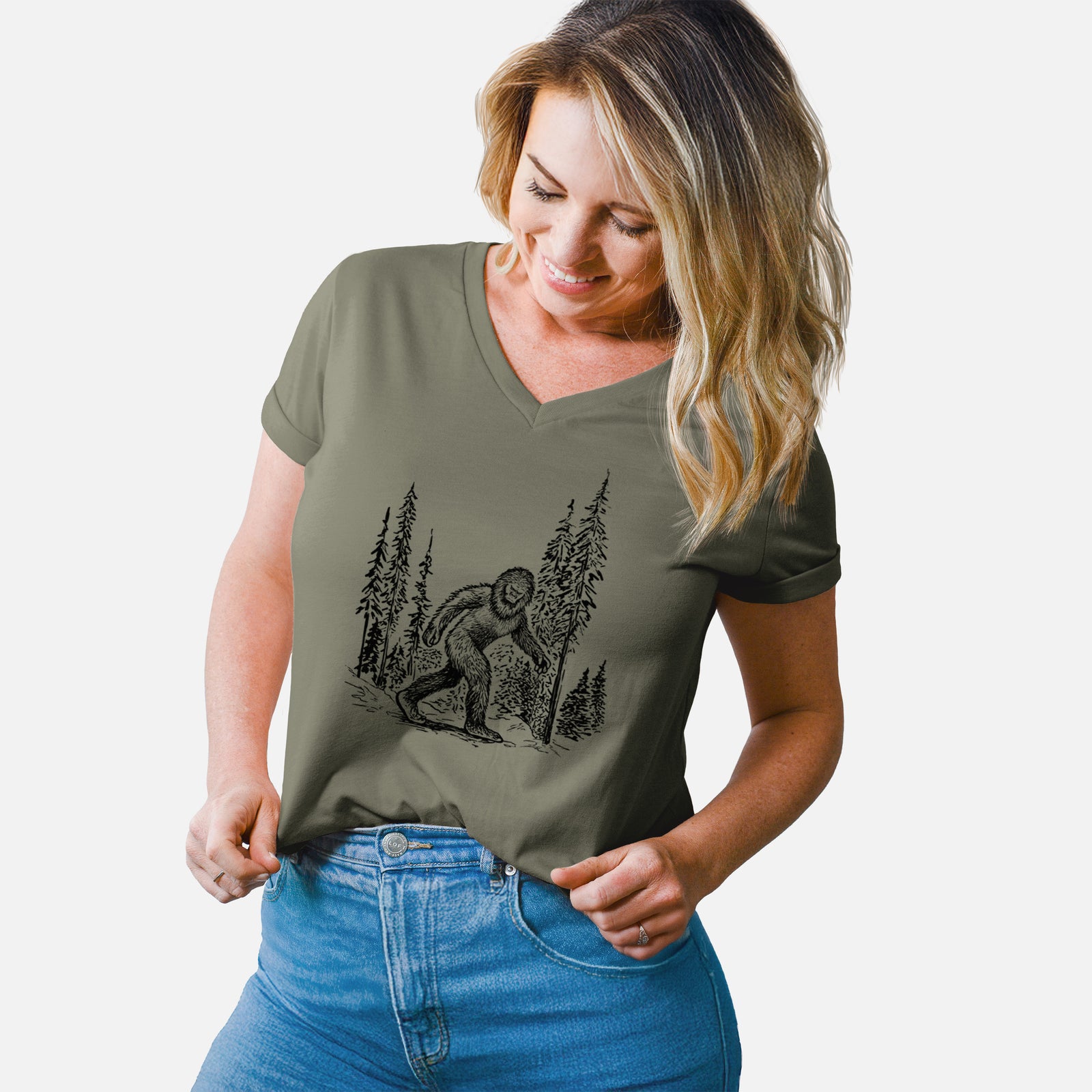 Turquoise women's relaxed fit cotton V-neck t-shirt laid flat, printed with a black ink illustration of Bigfoot walking through a pine forest.