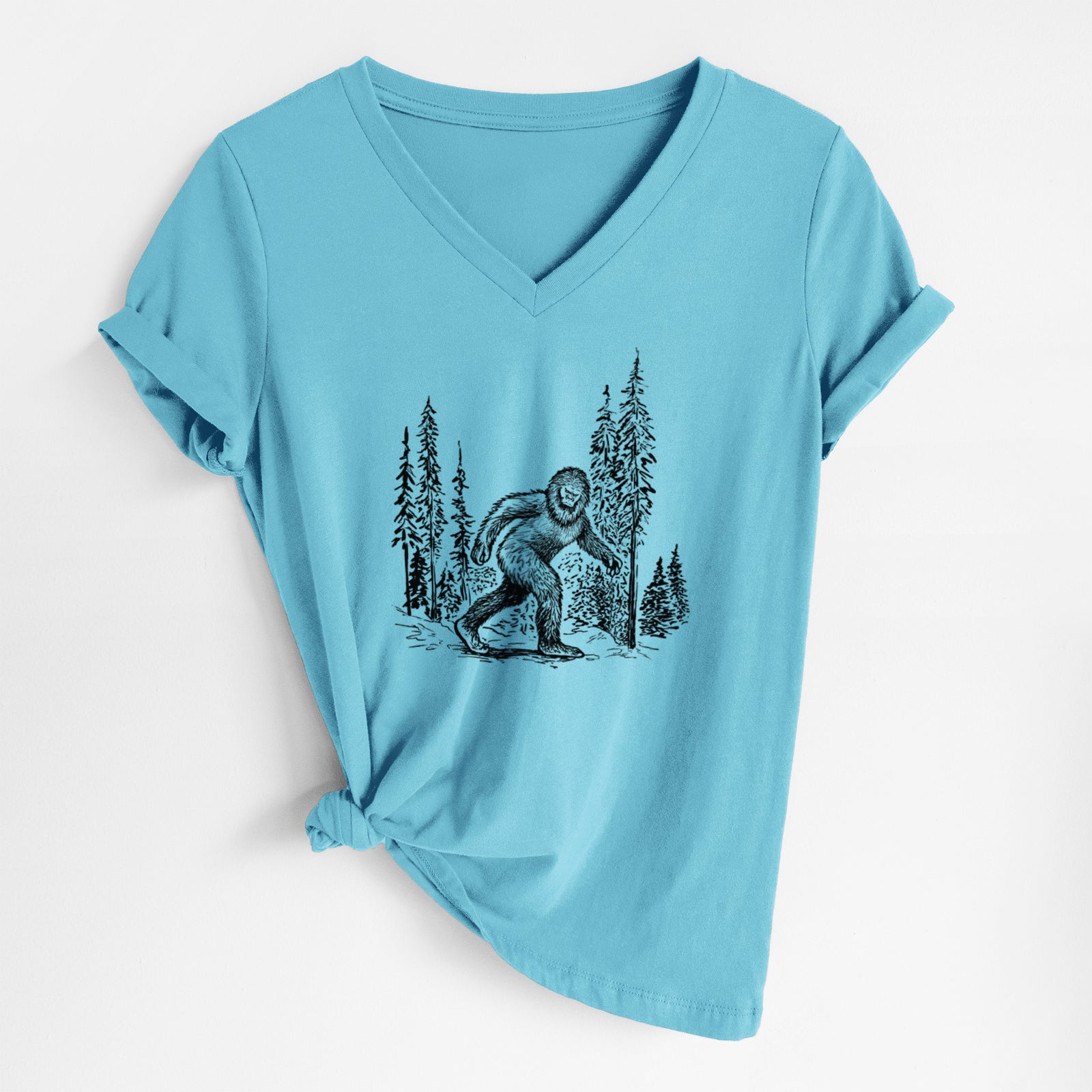 Turquoise women's relaxed fit cotton V-neck t-shirt laid flat, printed with a black ink illustration of Bigfoot walking through a pine forest.
