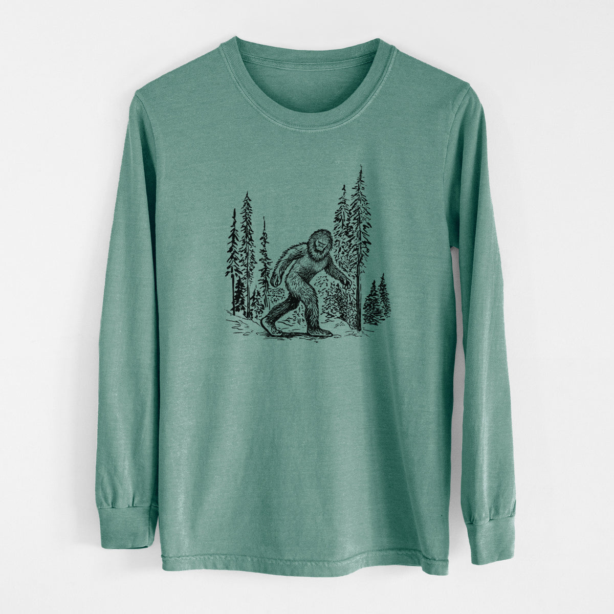 Pine green Comfort Colors long sleeve shirt laid flat, printed with a black ink illustration of Bigfoot walking through a pine forest.