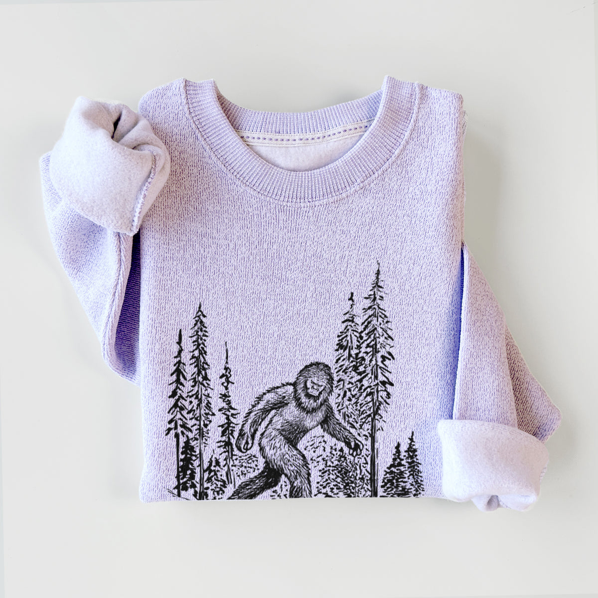 Ice purple knit sweatshirt printed with a black ink illustration of Bigfoot walking through a pine forest, styled flat.