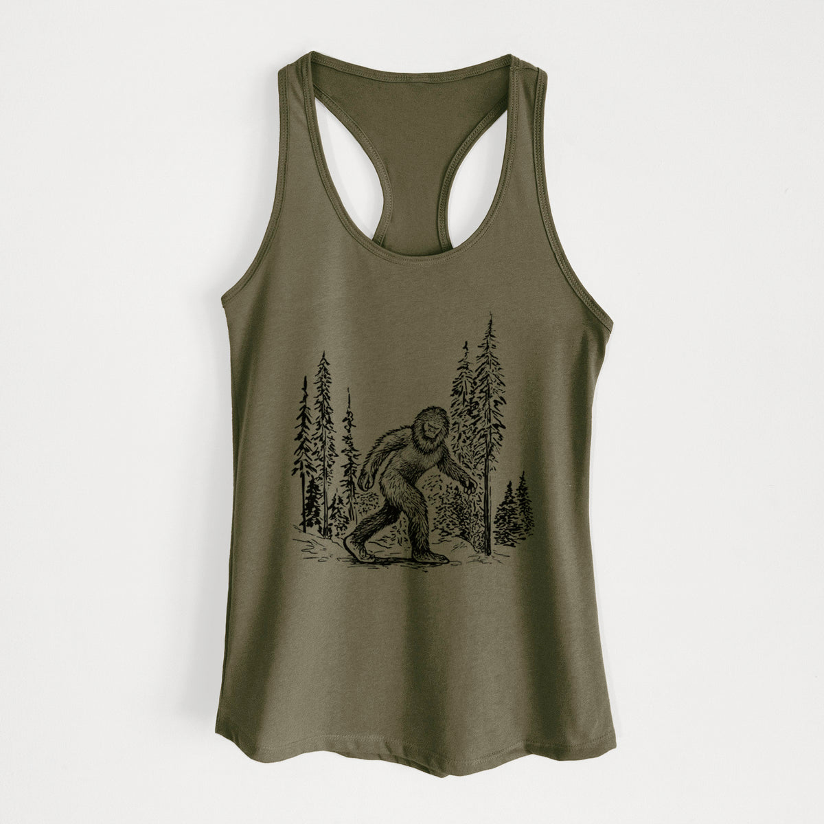 Military green women's racerback tank top laid flat, printed with a black ink illustration of Bigfoot walking through a pine forest.