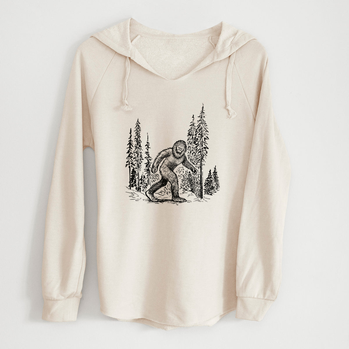 Bone cream women's Cali Wave hooded sweatshirt laid flat, printed with a black ink illustration of Bigfoot walking through a pine forest.