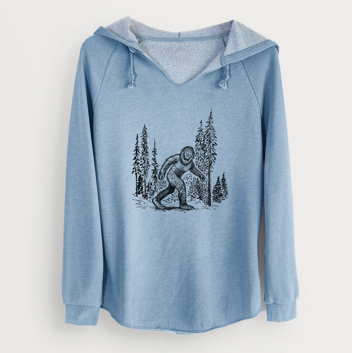 Misty blue women's Cali Wave hooded sweatshirt laid flat, printed with a black ink illustration of Bigfoot walking through a pine forest.