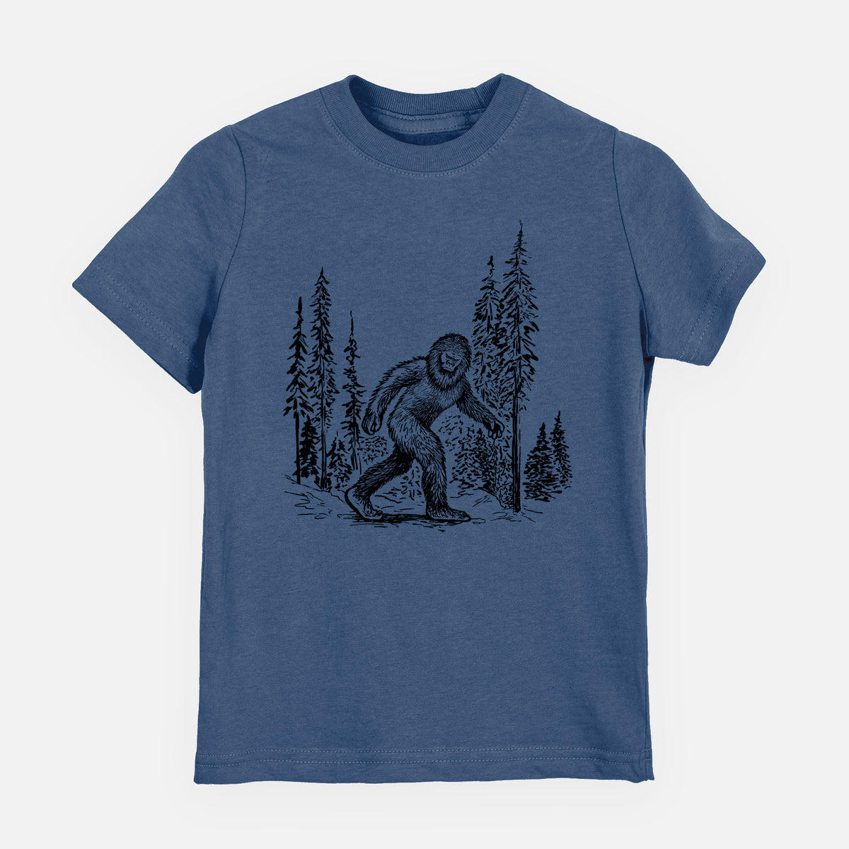 Indigo blue youth t-shirt laid flat, printed with a black ink illustration of Bigfoot walking through a pine forest.