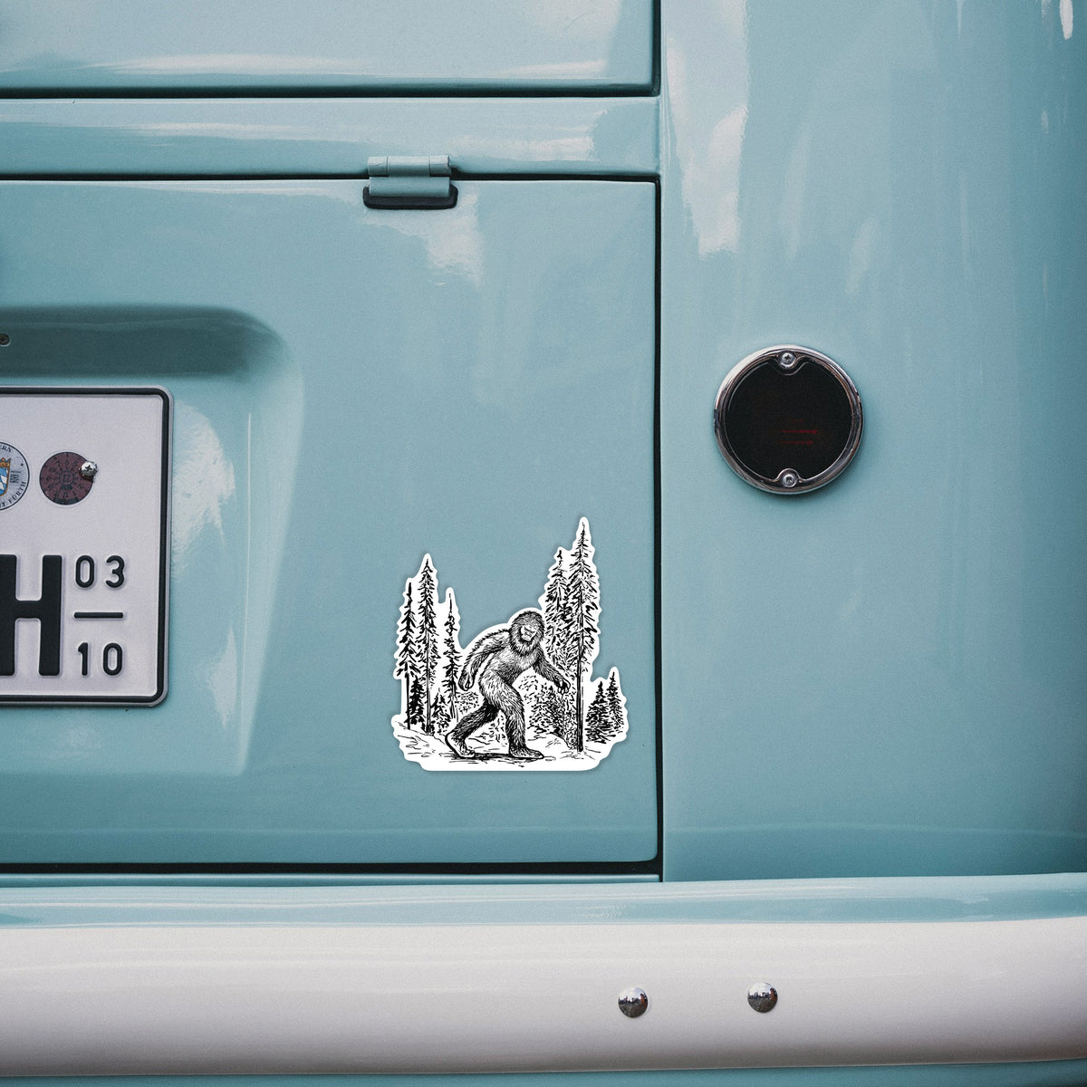 4 inch vinyl decal of a black ink illustration of Bigfoot walking through a pine forest on the back of a van.
