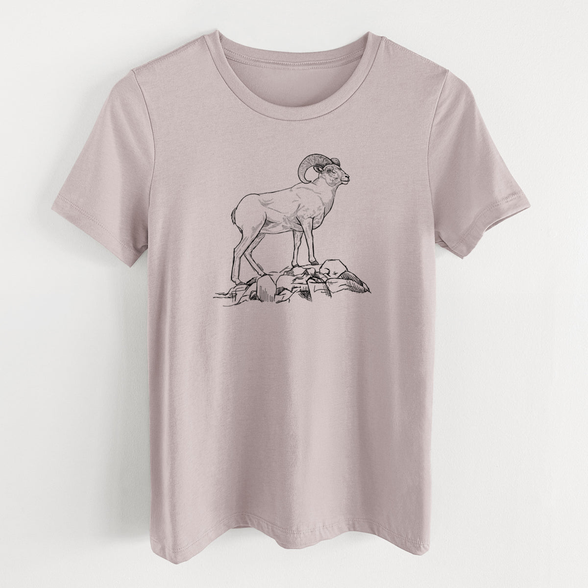 Pink gravel women's relaxed fit cotton t-shirt laid flat, printed with a black ink illustration of a bighorn ram with curled horns standing on rocks.