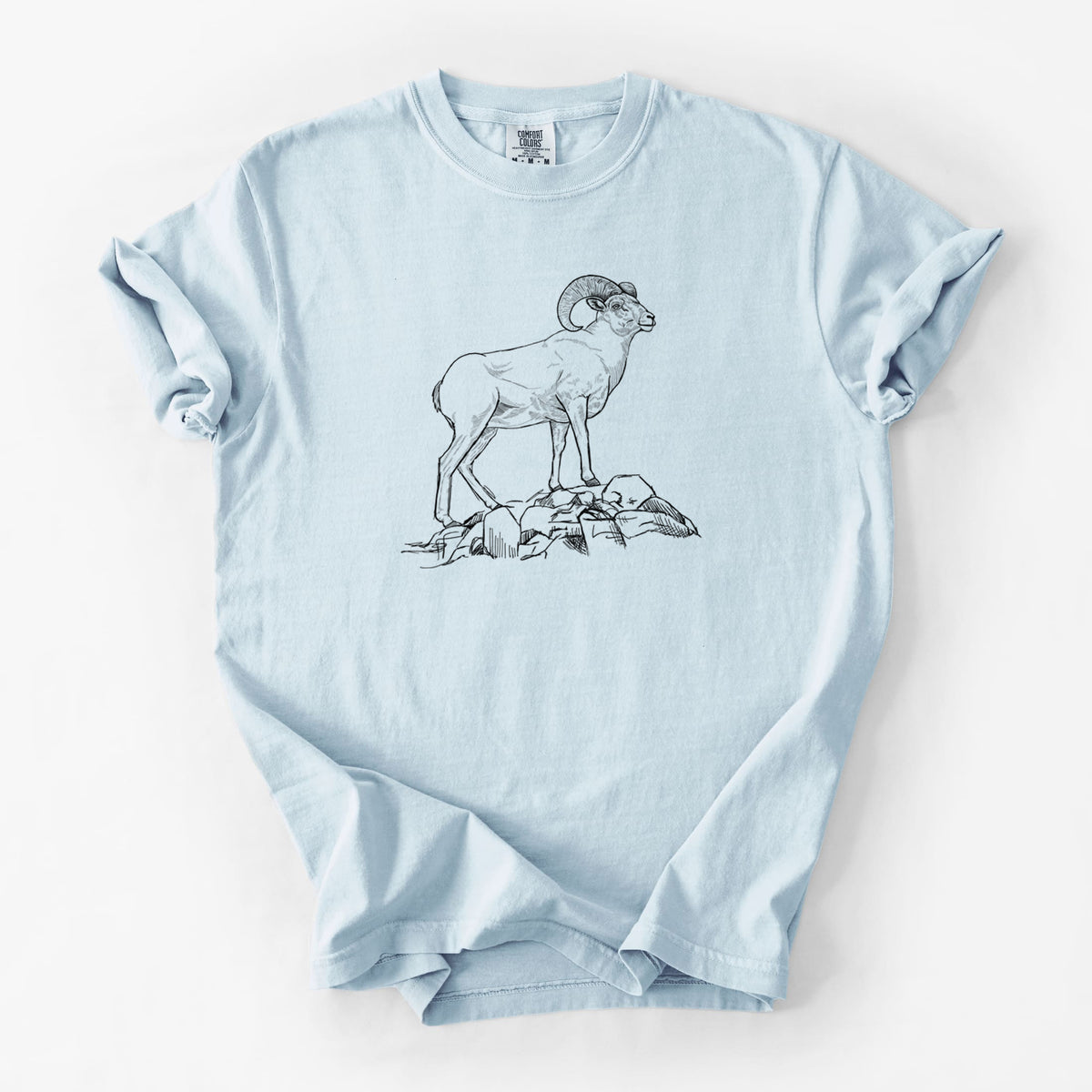 Chambray blue Comfort Colors t-shirt laid flat, printed with a black ink illustration of a bighorn ram with curled horns standing on rocks.