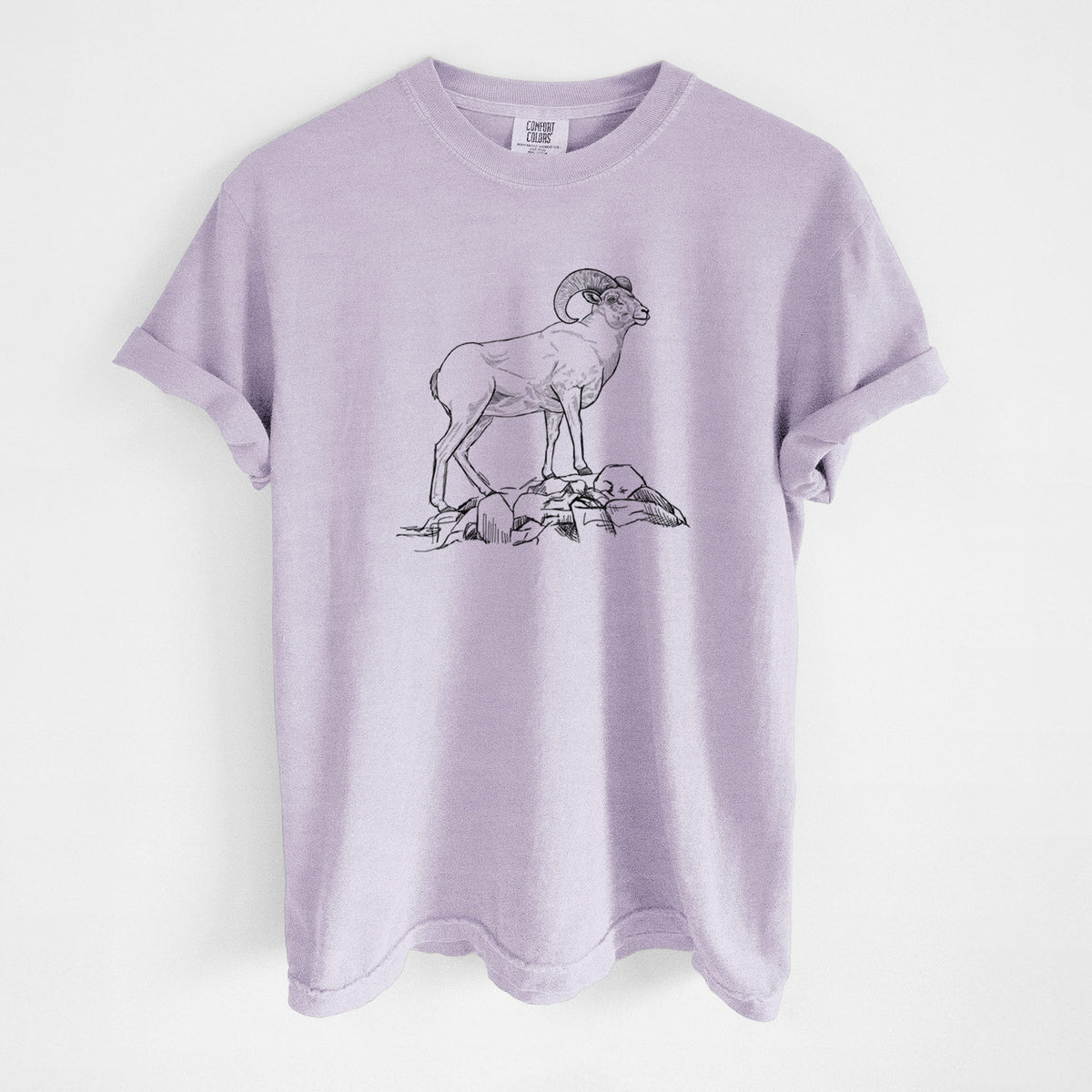 Orchid purple Comfort Colors t-shirt laid flat, printed with a black ink illustration of a bighorn ram with curled horns standing on rocks.
