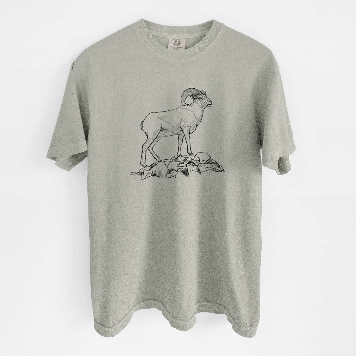 Sandstone beige Comfort Colors t-shirt laid flat, printed with a black ink illustration of a bighorn ram with curled horns standing on rocks.
