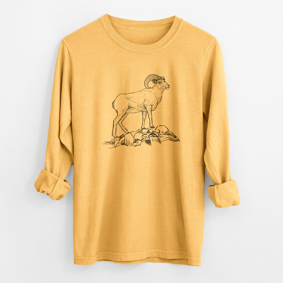 Golden wheat yellow Comfort Colors long sleeve shirt laid flat with the cuffs rolled, printed with a black ink illustration of a bighorn ram with curled horns standing on rocks.