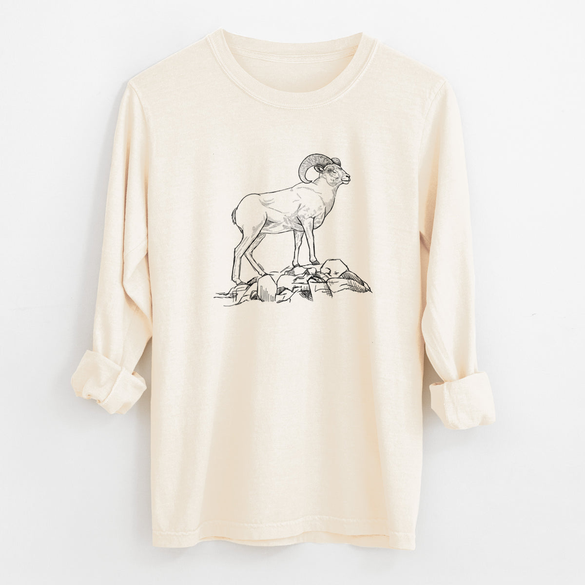 Ivory Comfort Colors long sleeve shirt laid flat with the cuffs rolled, printed with a black ink illustration of a bighorn ram with curled horns standing on rocks.