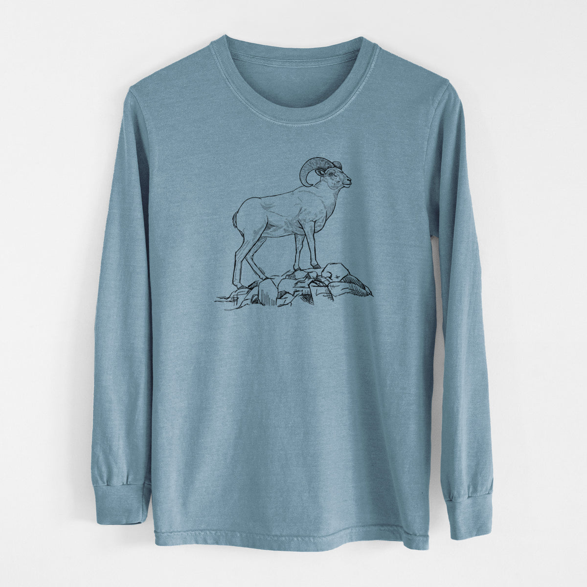 Steel blue Comfort Colors long sleeve shirt laid flat, printed with a black ink illustration of a bighorn ram with curled horns standing on rocks.