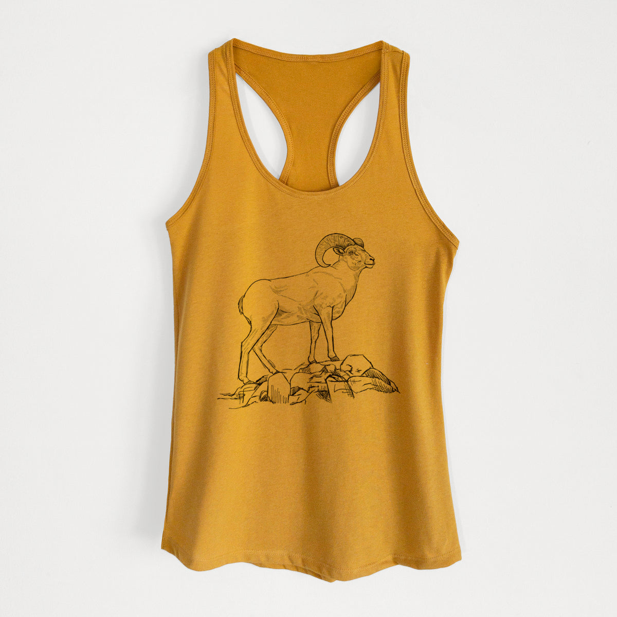 Gold women's racerback tank top laid flat, printed with a black ink illustration of a bighorn ram with curled horns standing on rocks.