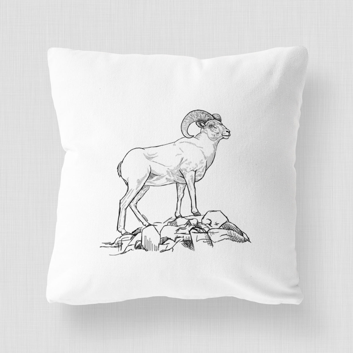 White pillow cover printed with a black ink illustration of a bighorn ram with curled horns standing on rocks.