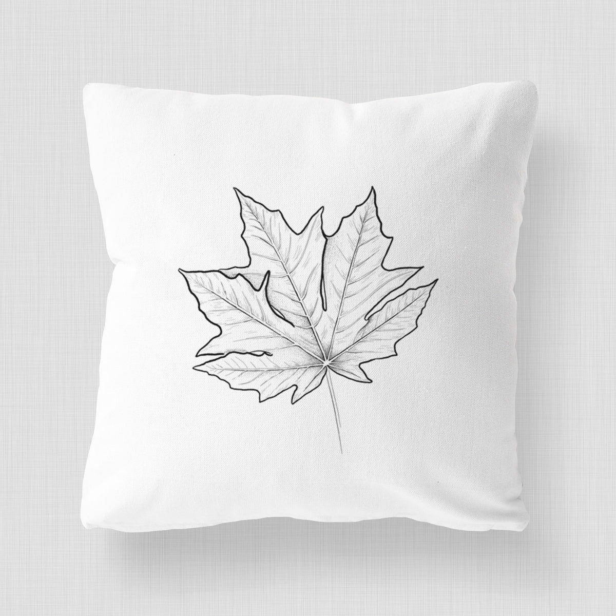 White pillow cover printed with a black ink line drawing of a bigleaf maple leaf.