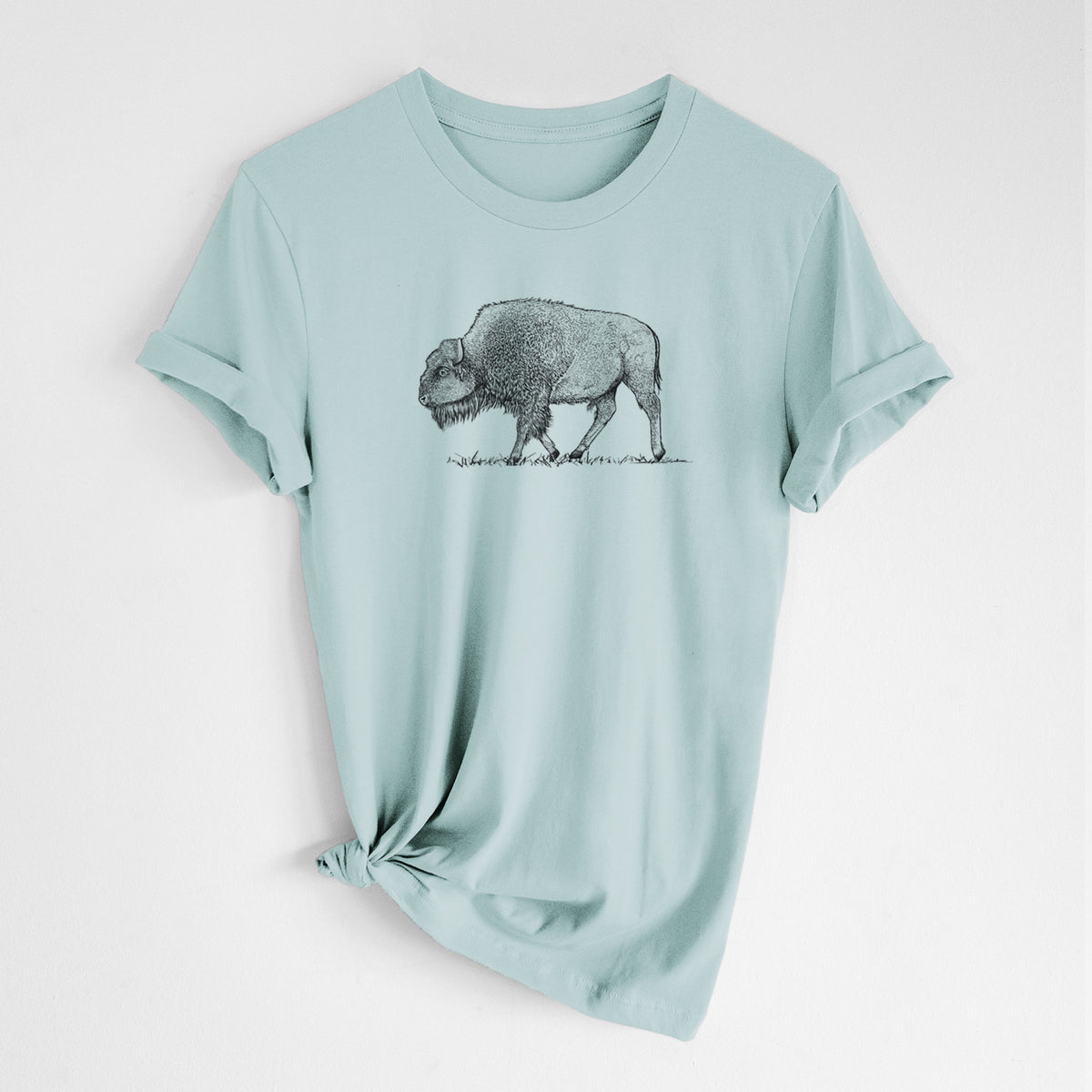 Dusty blue lightweight cotton t-shirt laid flat with the sleeves rolled, printed with a detailed black ink illustration of an American bison walking through grass.