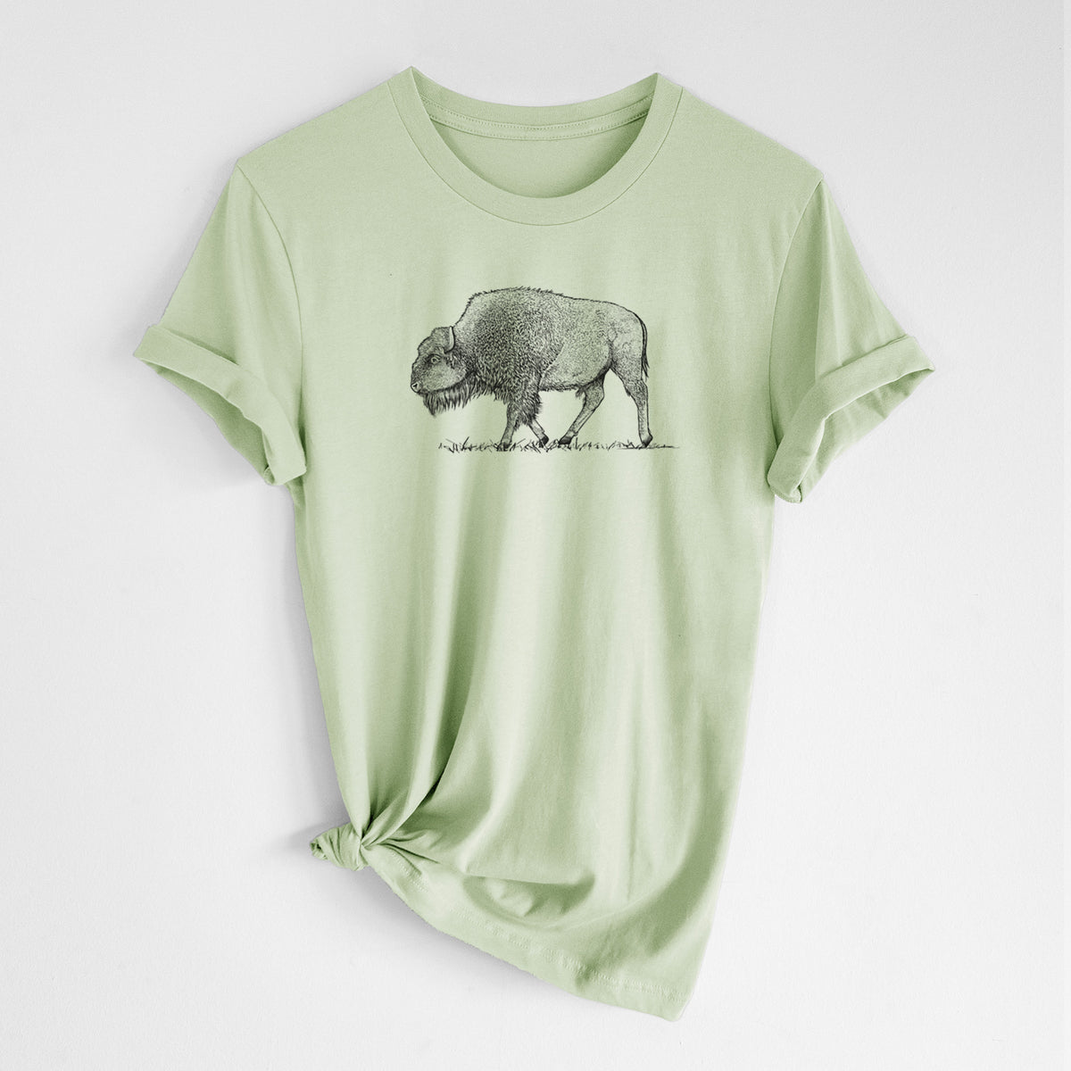 Spring green lightweight cotton t-shirt laid flat with the sleeves rolled, printed with a detailed black ink illustration of an American bison walking through grass.