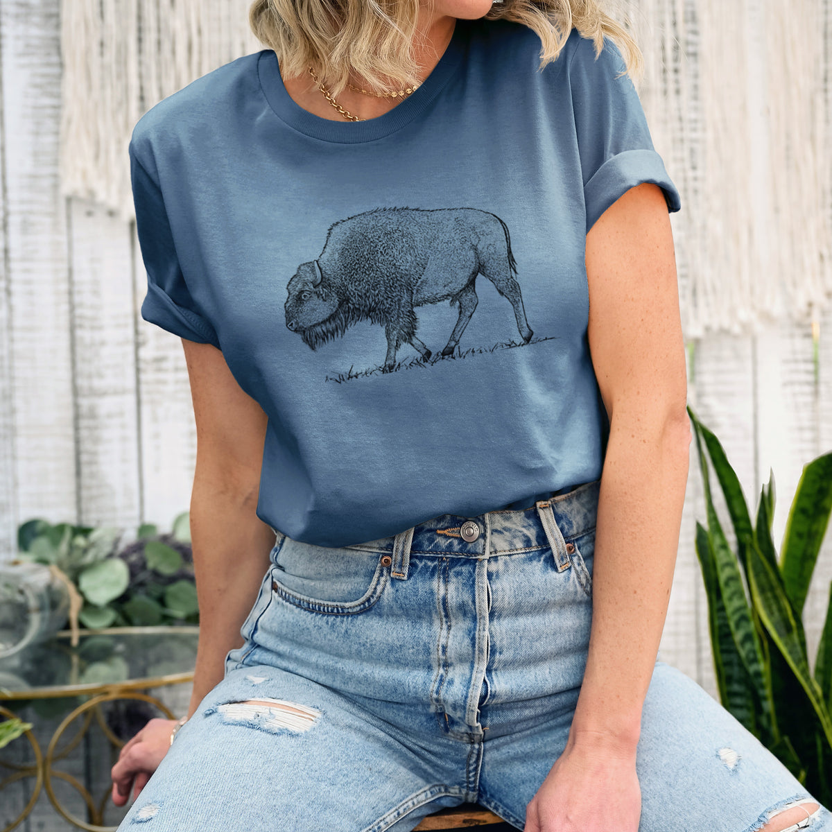 Woman wearing a steel blue lightweight cotton t-shirt printed with a detailed black ink illustration of an American bison walking through grass.
