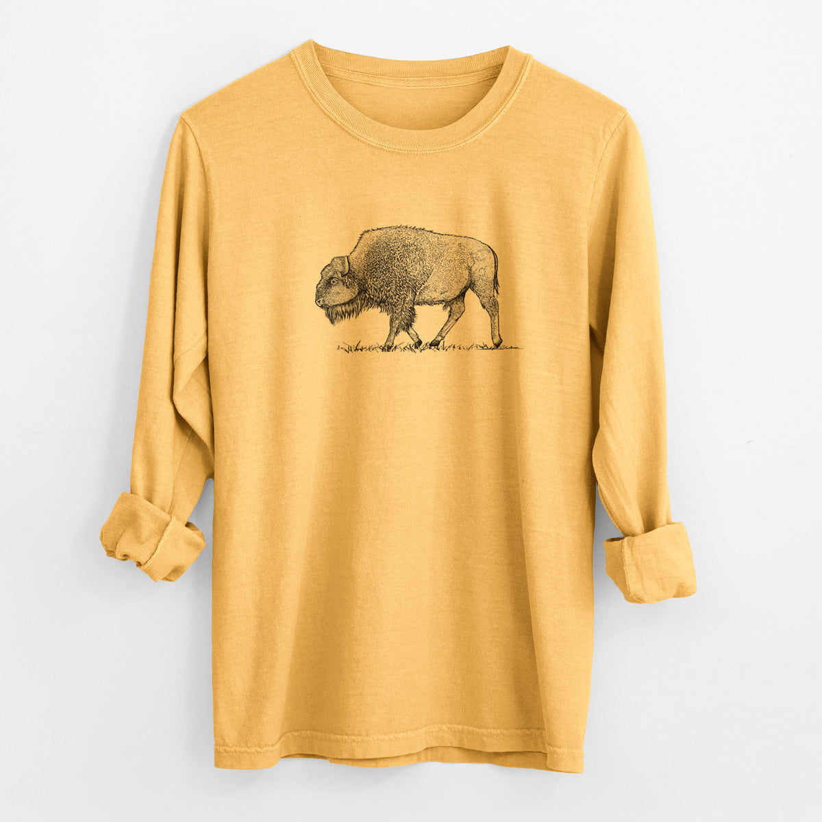 Golden wheat yellow Comfort Colors long sleeve shirt laid flat with the cuffs rolled, printed with a detailed black ink illustration of an American bison walking through grass.