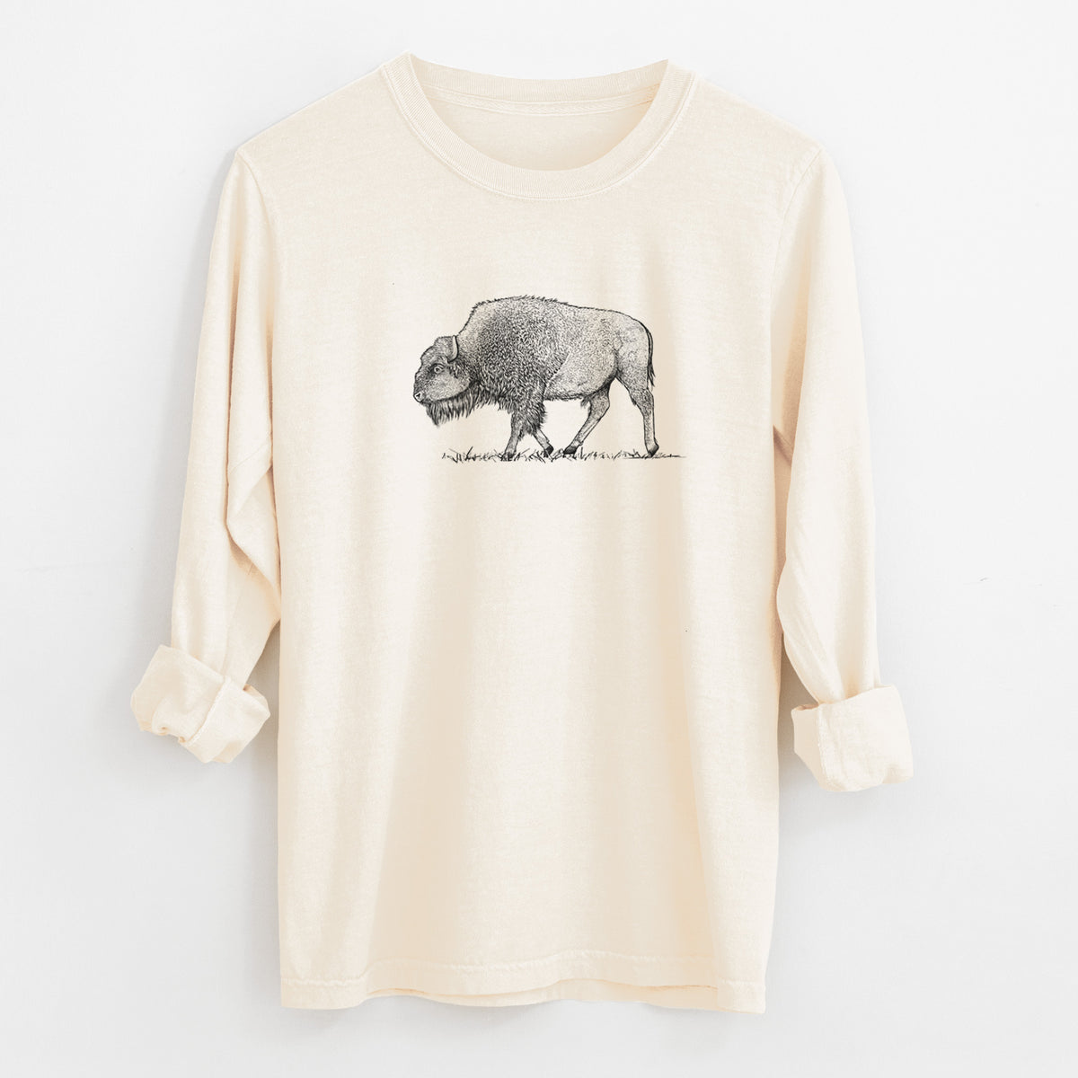 Ivory Comfort Colors long sleeve shirt laid flat with the cuffs rolled, printed with a detailed black ink illustration of an American bison walking through grass.