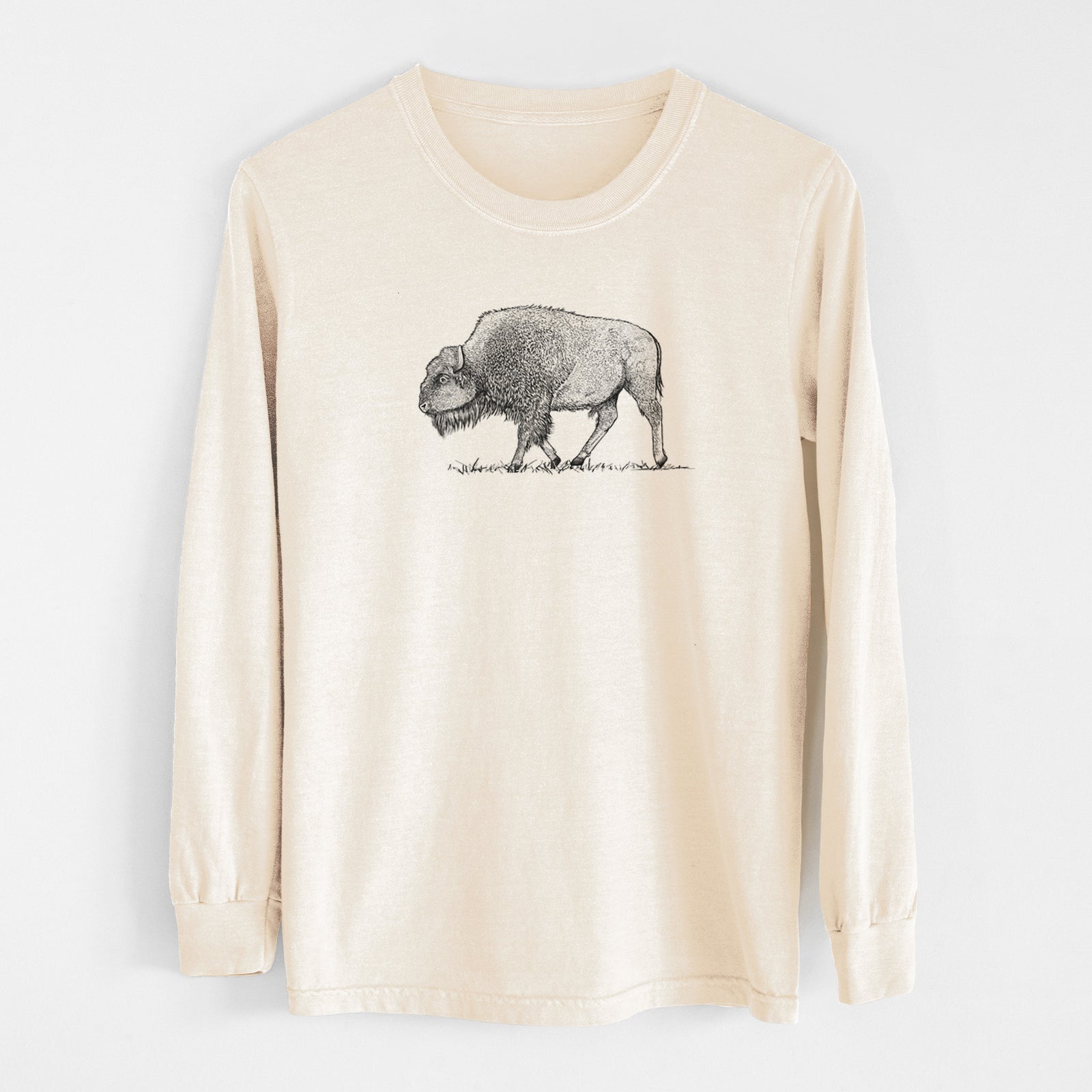 Ivory Comfort Colors long sleeve shirt laid flat, printed with a detailed black ink illustration of an American bison walking through grass.
