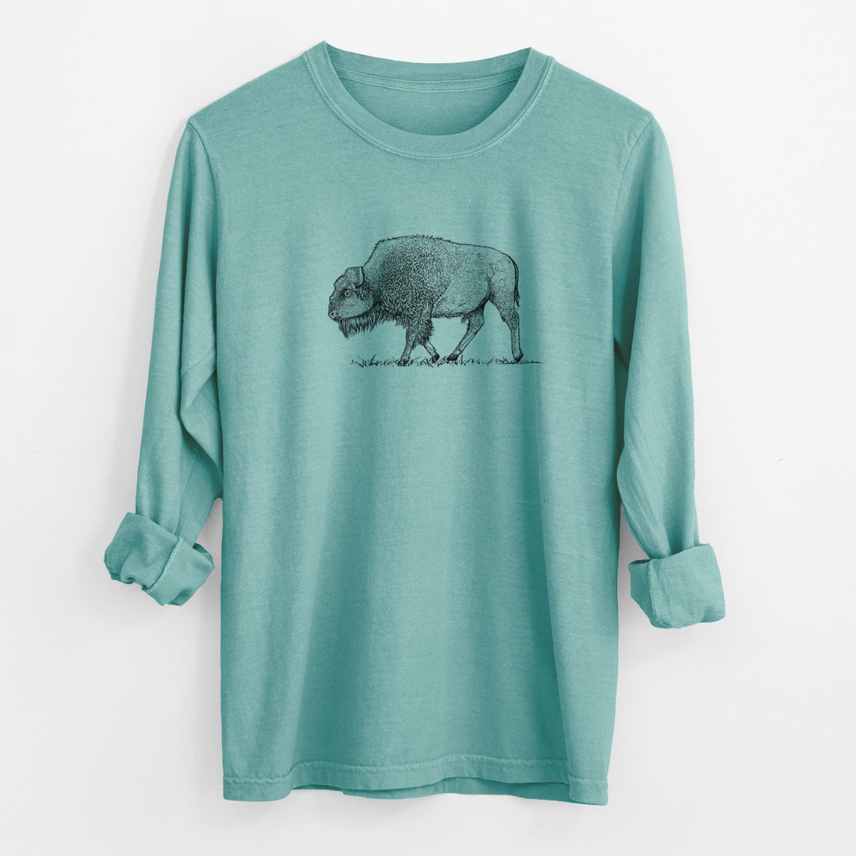 Reef green Comfort Colors long sleeve shirt laid flat with the cuffs rolled, printed with a detailed black ink illustration of an American bison walking through grass.