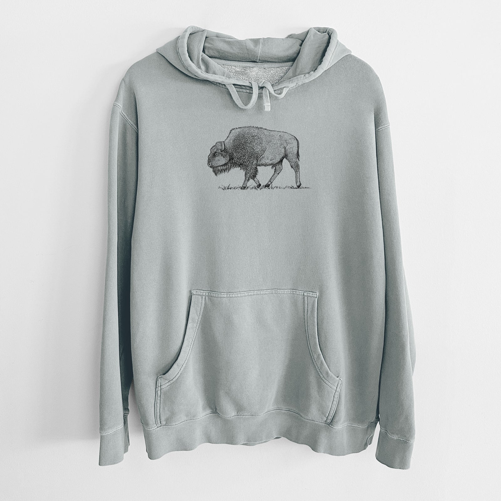 Sage green pigment dyed hoodie laid flat, printed with a detailed black ink illustration of an American bison walking through grass.