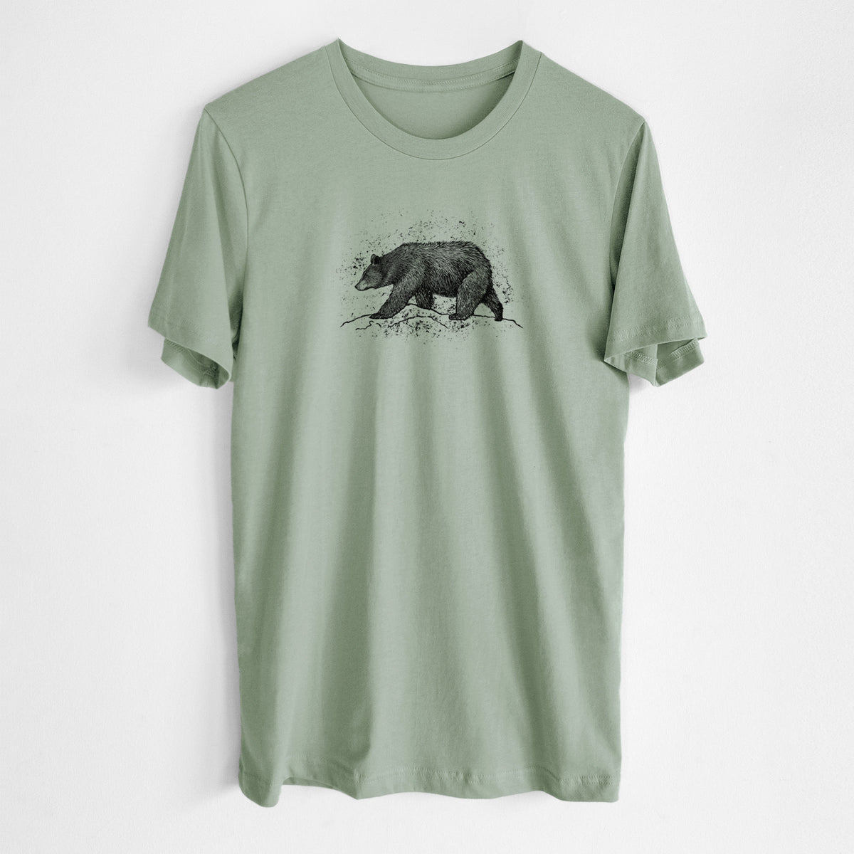 Sage green lightweight cotton t-shirt laid flat, printed with a detailed black ink sketch of a black bear walking across rocky ground.