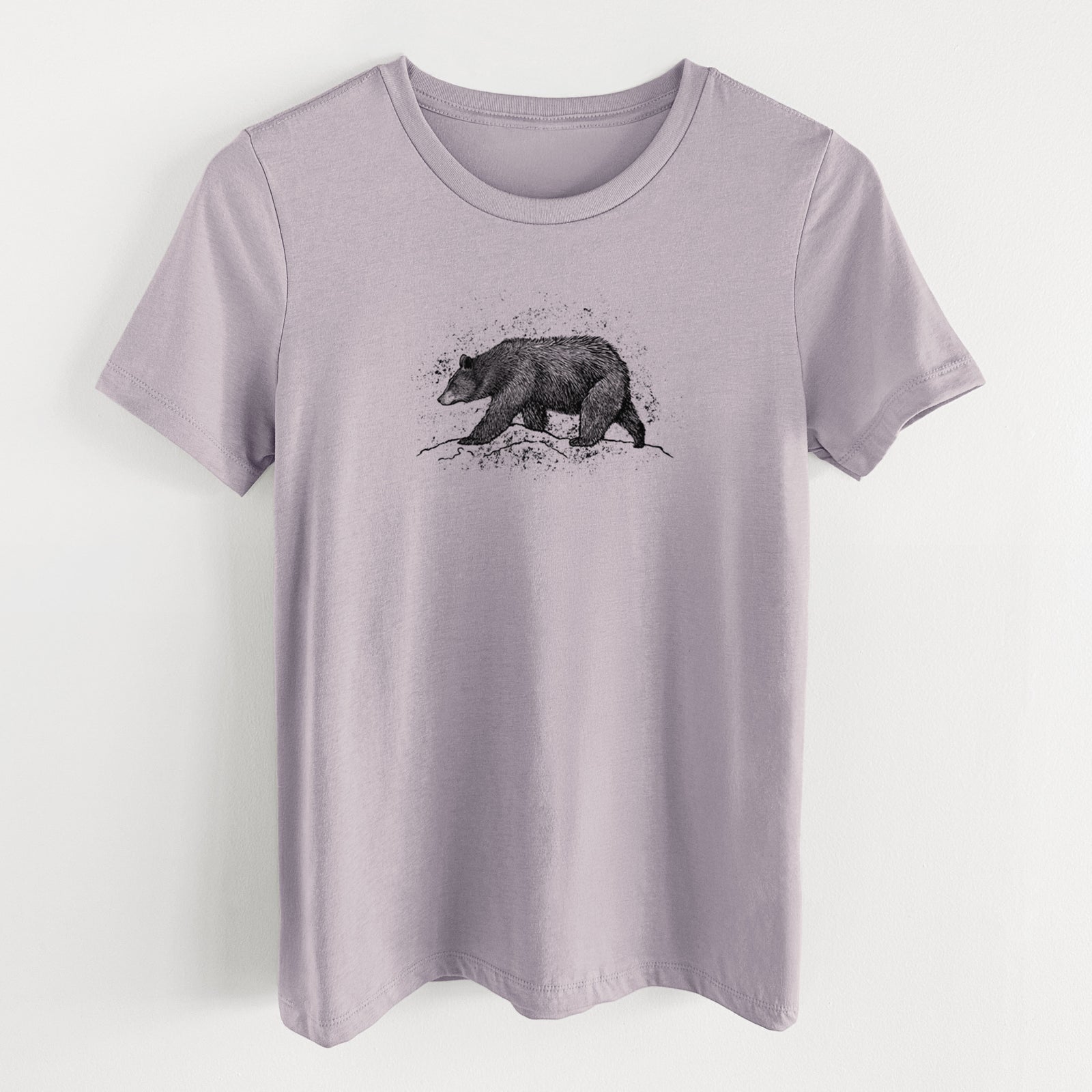 Light violet women's relaxed fit cotton t-shirt laid flat, printed with a detailed black ink sketch of a black bear walking across rocky ground.