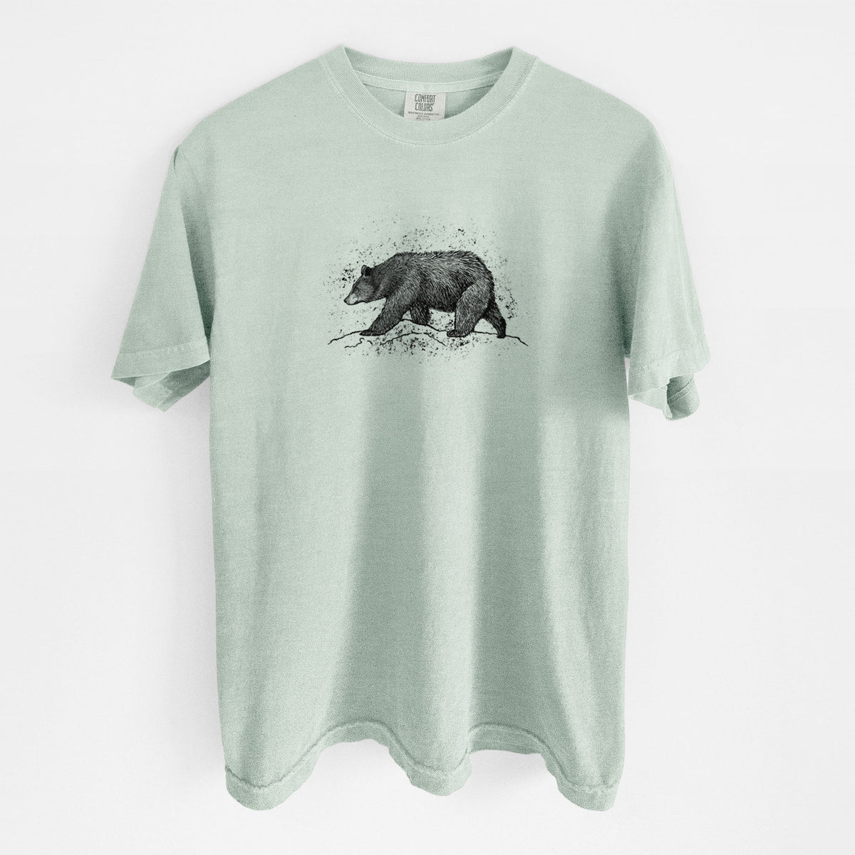 Bay green Comfort Colors t-shirt laid flat, printed with a detailed black ink sketch of a black bear walking across rocky ground.