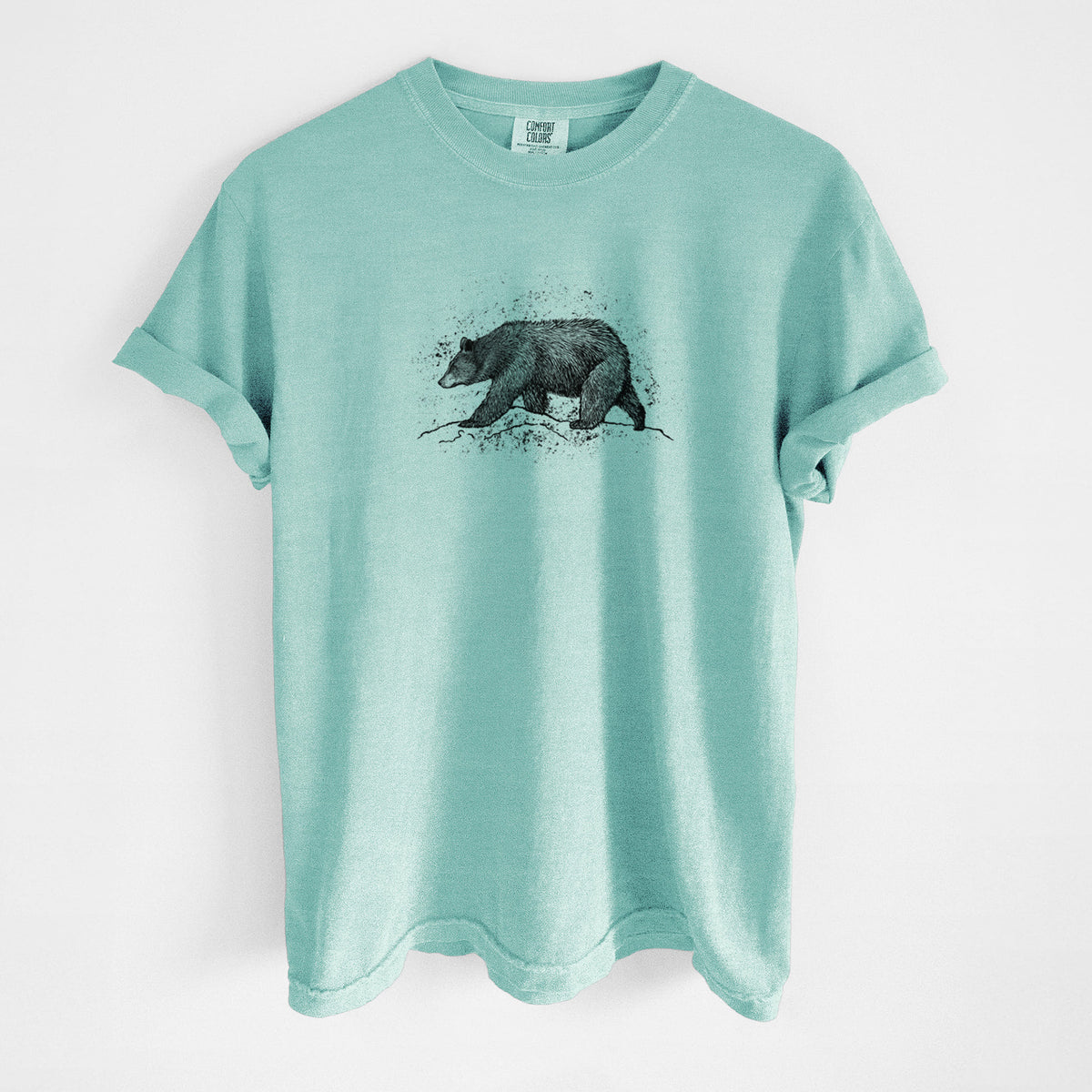 Chalky mint Comfort Colors t-shirt laid flat, printed with a detailed black ink sketch of a black bear walking across rocky ground.