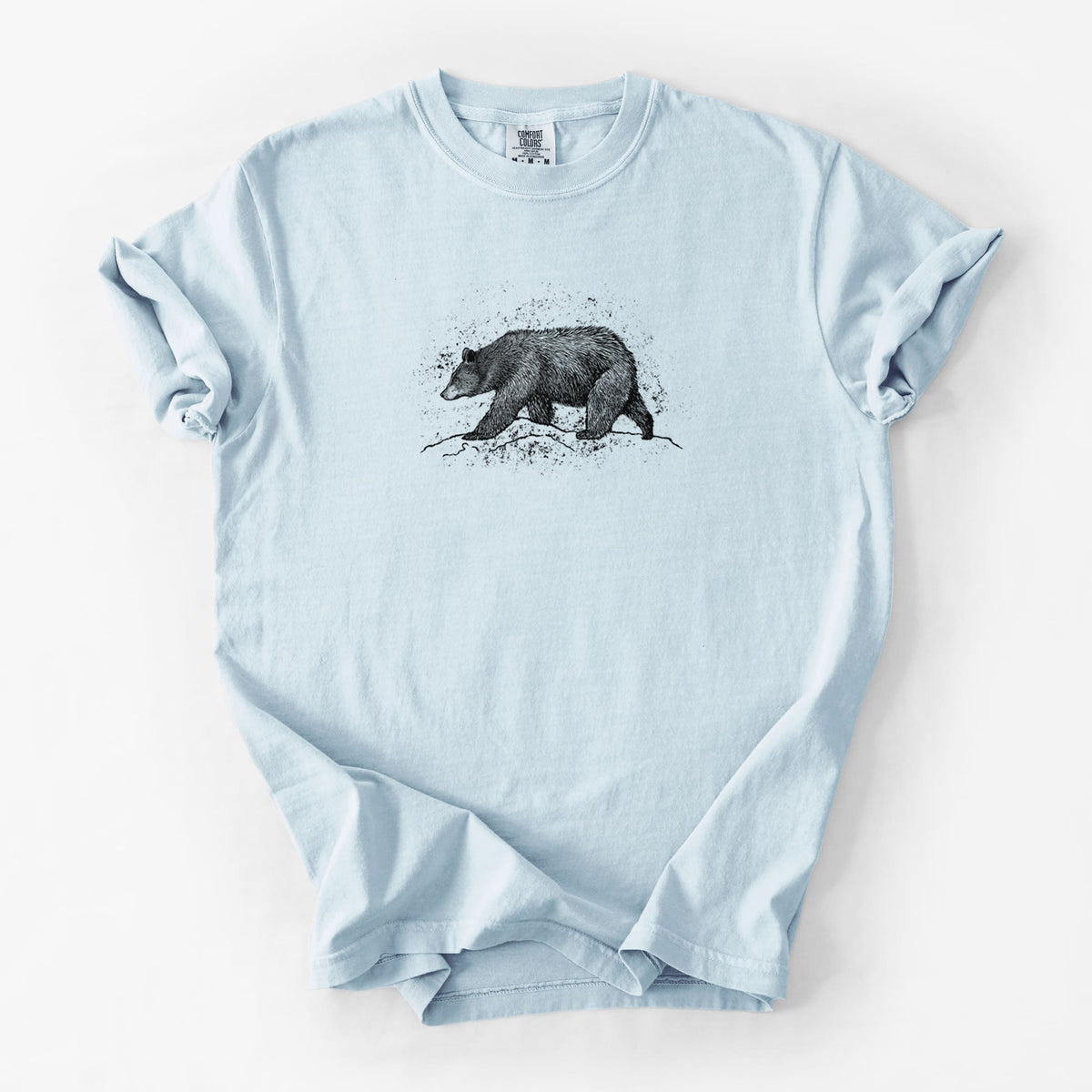 Chambray blue Comfort Colors t-shirt laid flat, printed with a detailed black ink sketch of a black bear walking across rocky ground.