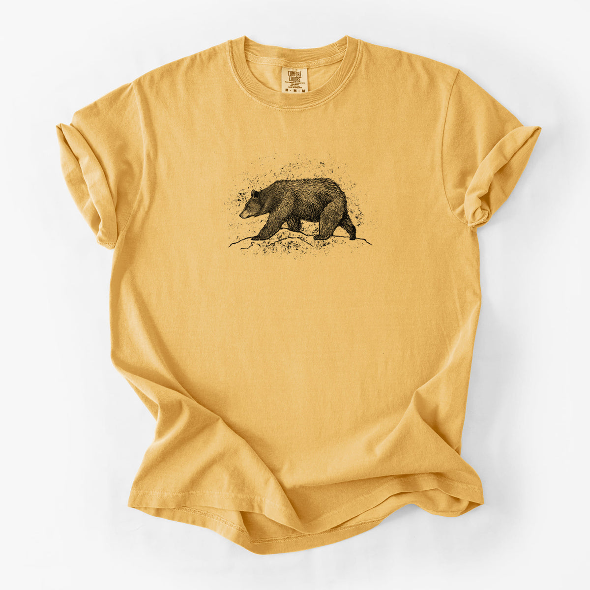 Golden wheat yellow Comfort Colors t-shirt laid flat, printed with a detailed black ink sketch of a black bear walking across rocky ground.