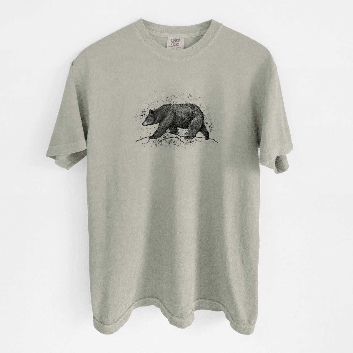 Sandstone beige Comfort Colors t-shirt laid flat, printed with a detailed black ink sketch of a black bear walking across rocky ground.