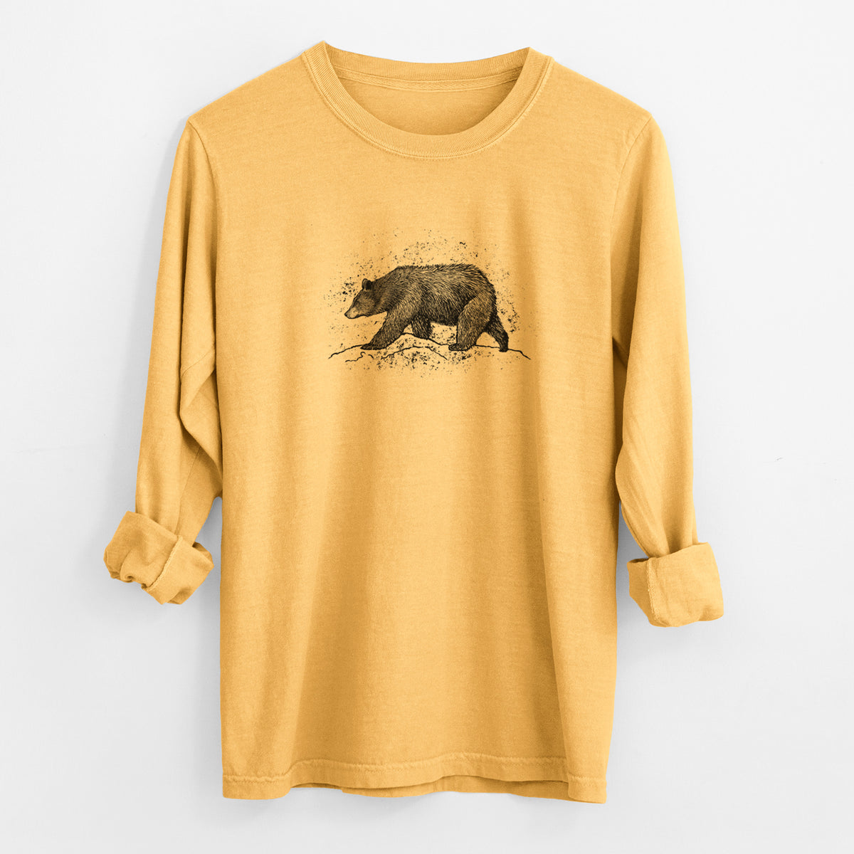 Golden wheat yellow Comfort Colors long sleeve shirt laid flat with the cuffs rolled, printed with a detailed black ink sketch of a black bear walking across rocky ground.