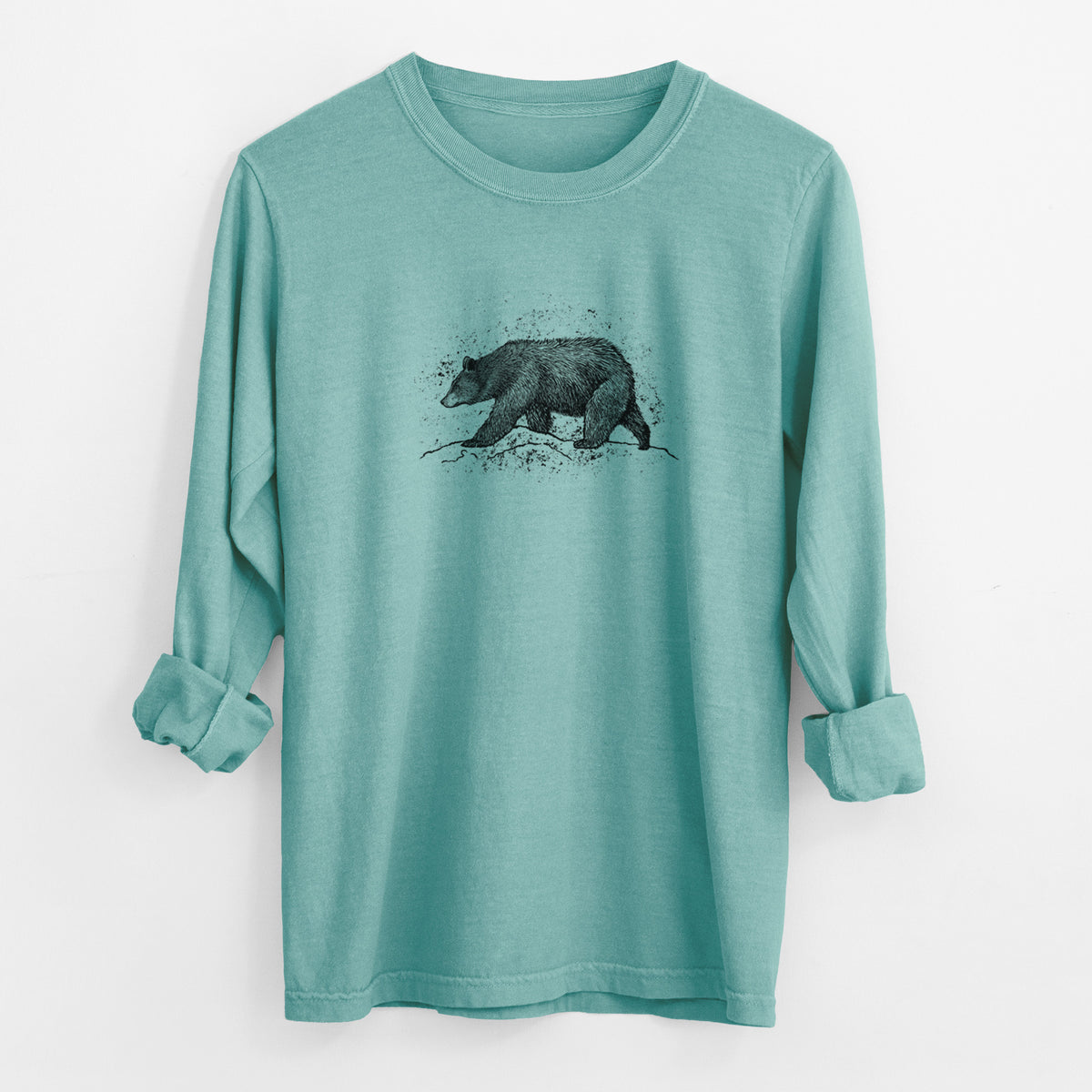 Reef green Comfort Colors long sleeve shirt laid flat with the cuffs rolled, printed with a detailed black ink sketch of a black bear walking across rocky ground.