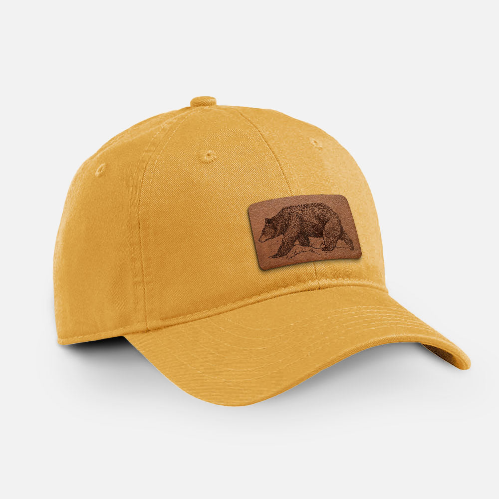 Beehive yellow cotton baseball hat with a detailed black ink sketch of a black bear walking across rocky ground on the front.