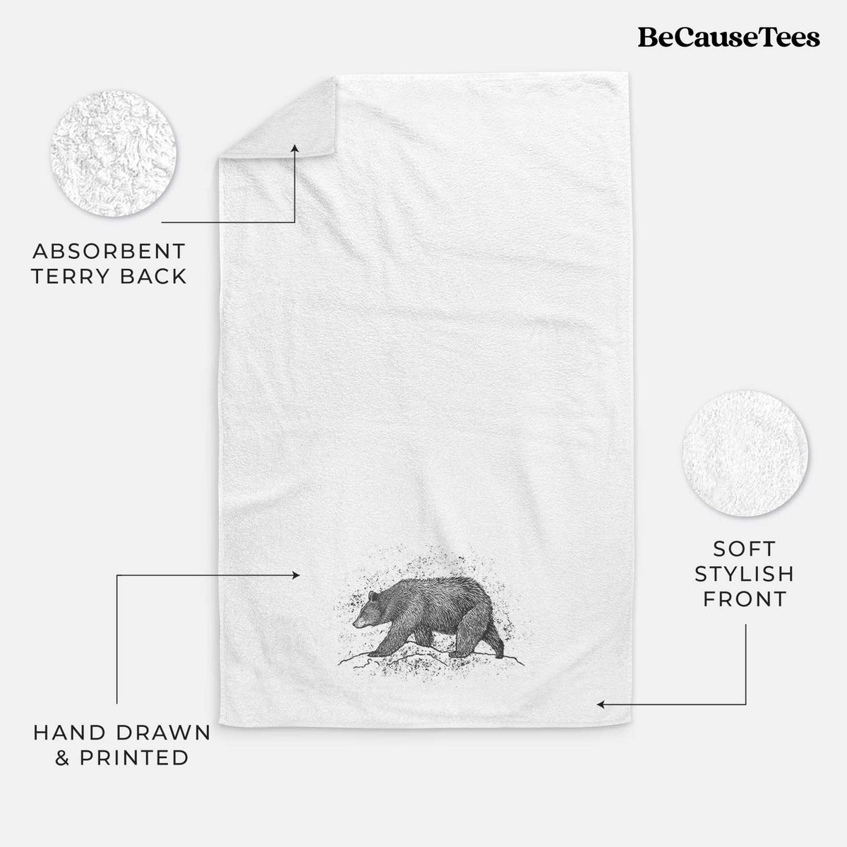 White hand towel printed with a detailed black ink sketch of a black bear walking across rocky ground.