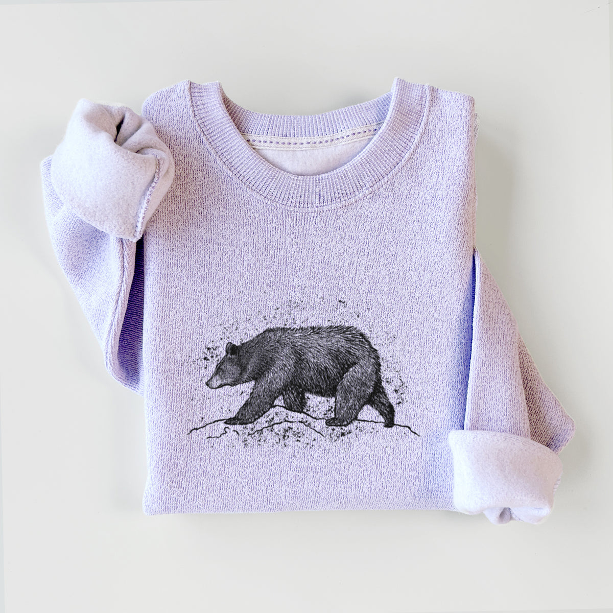 Ice purple knit sweatshirt printed with a detailed black ink sketch of a black bear walking across rocky ground, styled flat.