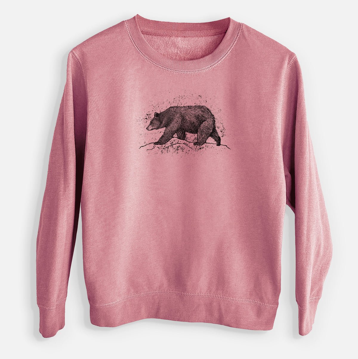 Mauve pink youth crewneck sweatshirt laid flat, printed with a detailed black ink sketch of a black bear walking across rocky ground.