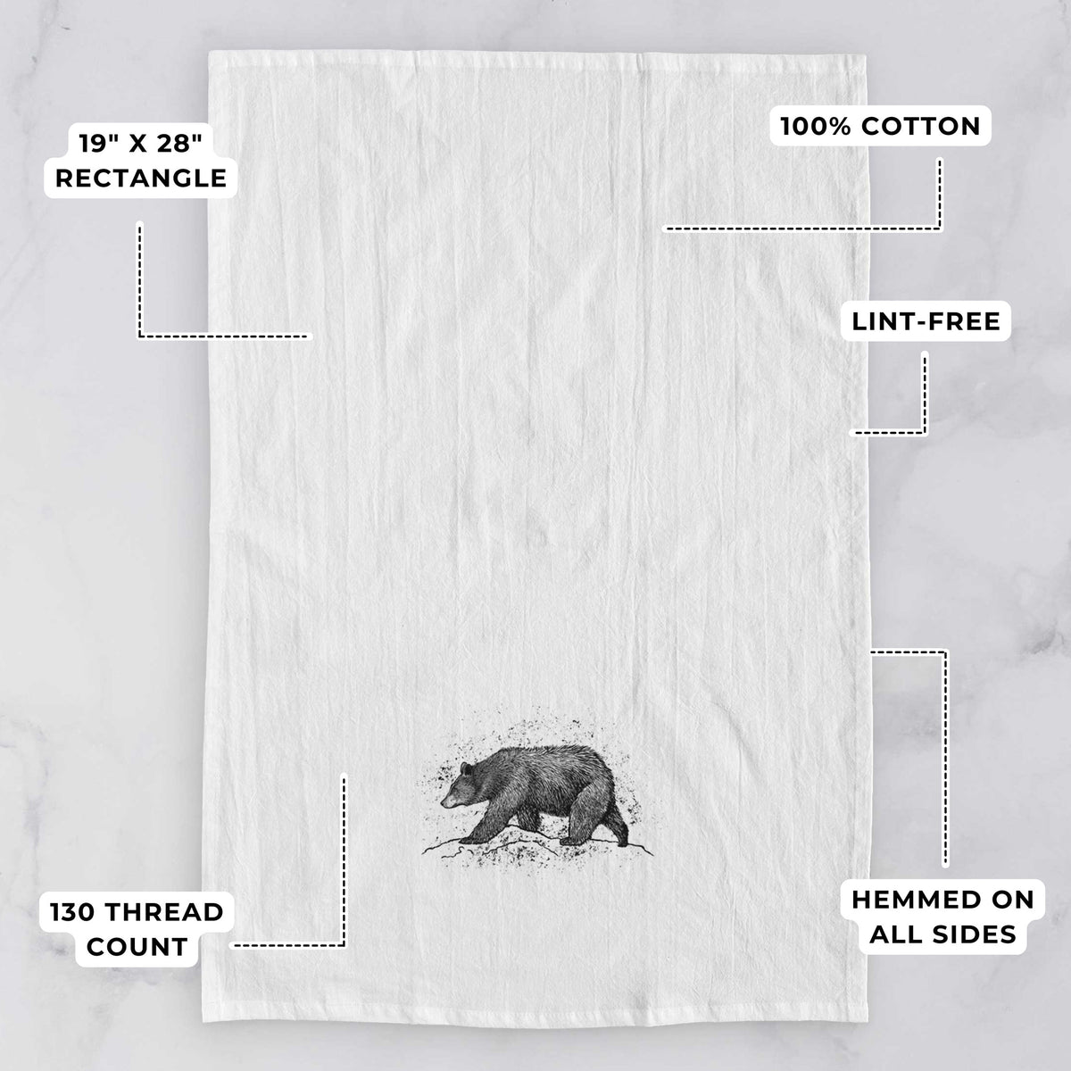 White tea towel printed with a detailed black ink sketch of a black bear walking across rocky ground, with feature labels: 19 by 28 inch rectangle, 100% cotton, lint-free, 130 thread count, hemmed on all sides.