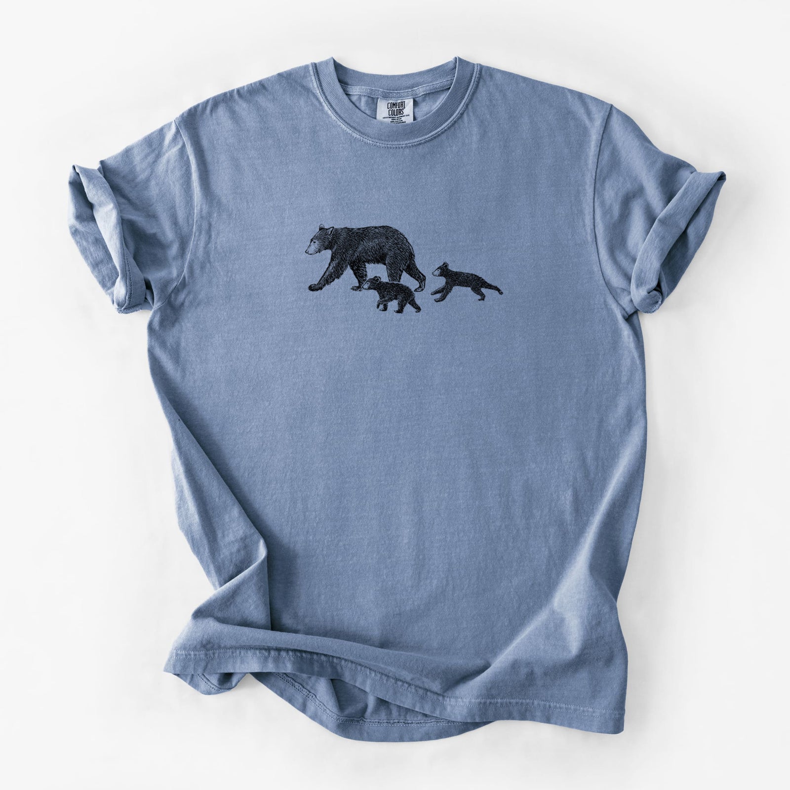Blue jean Comfort Colors t-shirt laid flat, printed with a black ink illustration of a mother black bear walking with two cubs.