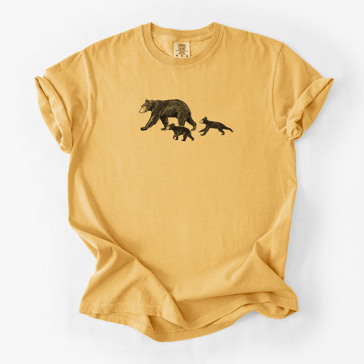Golden wheat yellow Comfort Colors t-shirt laid flat, printed with a black ink illustration of a mother black bear walking with two cubs.