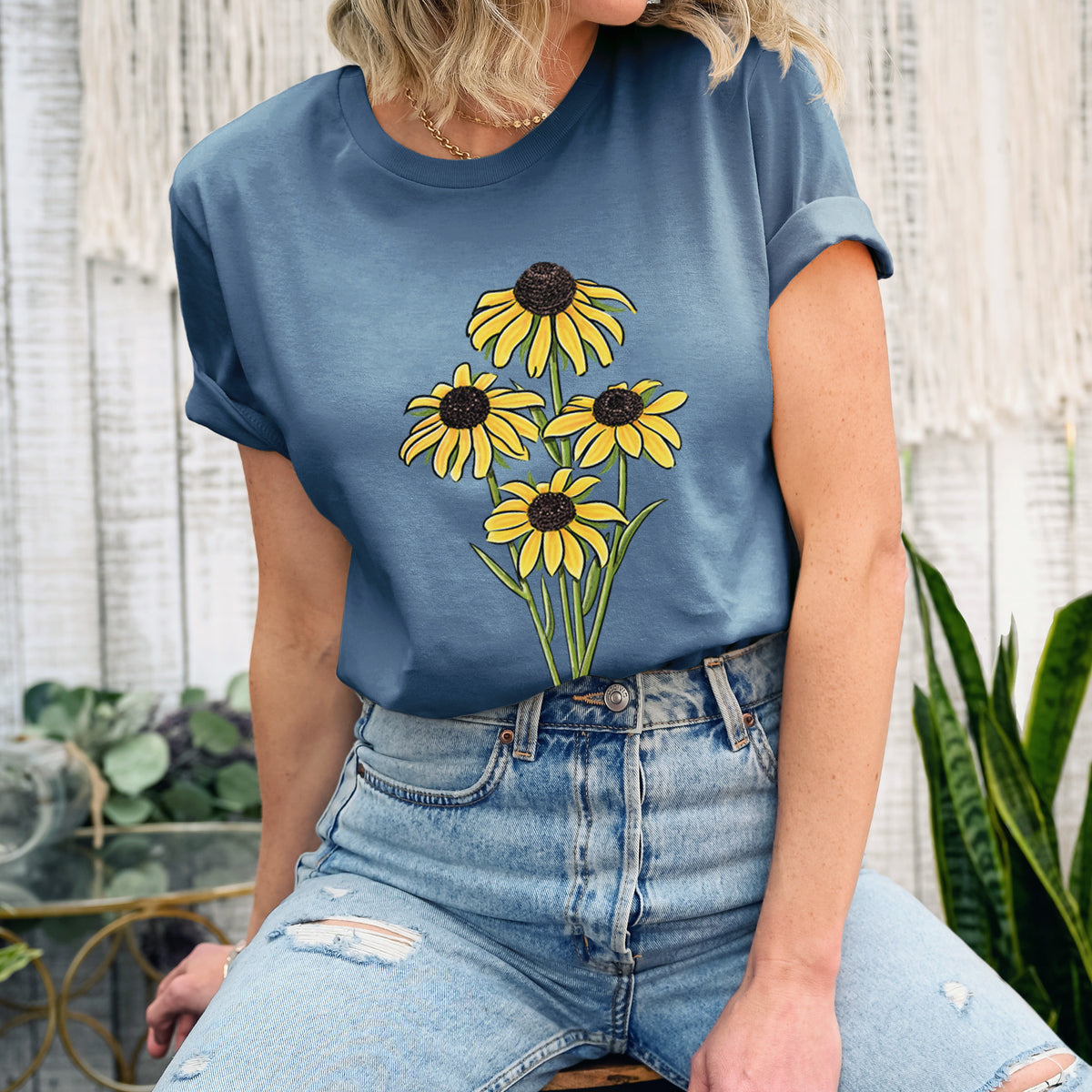Woman wearing a steel blue lightweight cotton t-shirt printed with a full-color bouquet of yellow black-eyed Susan flowers.