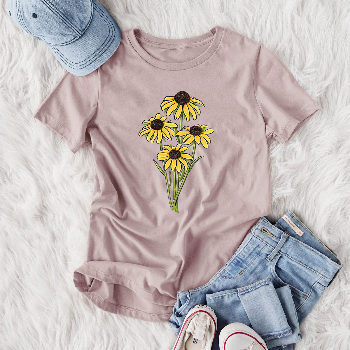 Women's relaxed fit cotton t-shirt printed with a full-color bouquet of yellow black-eyed Susan flowers, styled flat on a white faux fur rug with jeans.