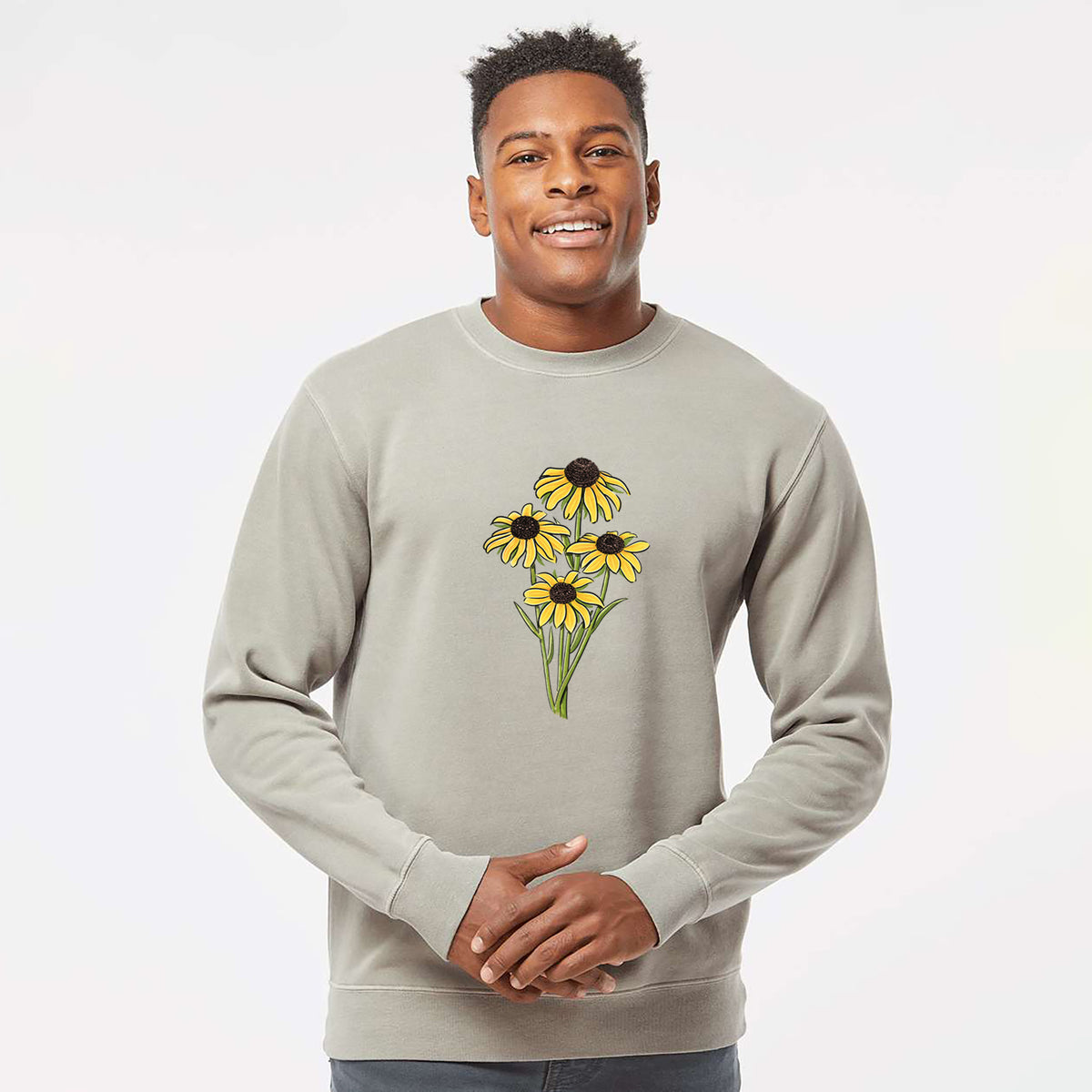 Model wearing a cement grey pigment dyed crewneck sweatshirt printed with a full-color bouquet of yellow black-eyed Susan flowers.