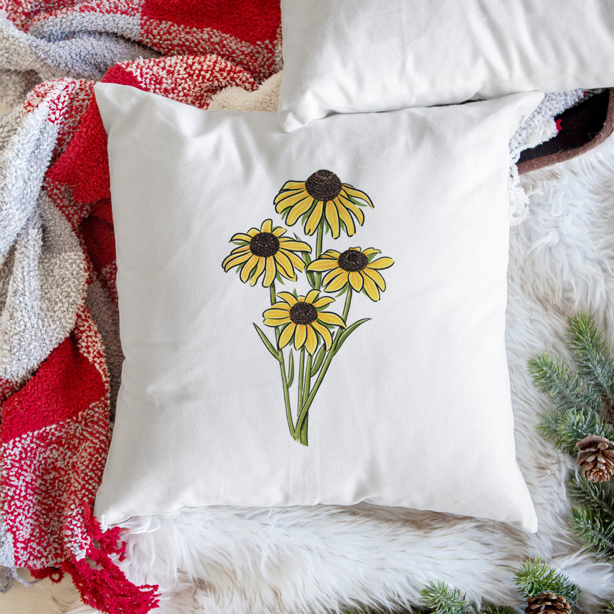 White pillow cover printed with a full-color bouquet of yellow black-eyed Susan flowers, on a woven chair.